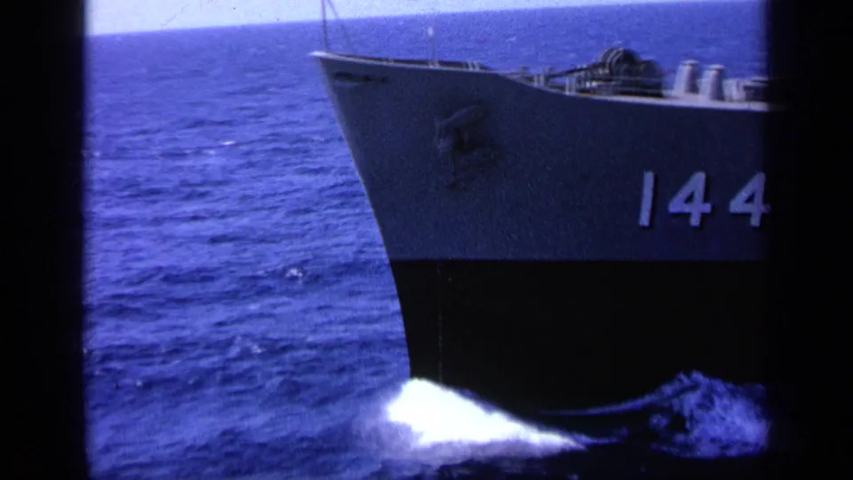 1963 Greece reel frame showing the bow of a naval vessel cutting through blue water, with hull number 144 visible on the side.