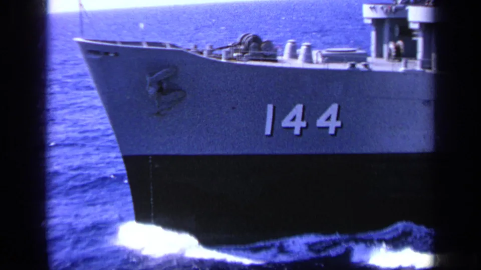 1963 Greece reel frame with a closer view of a naval vessel bow marked 144, deck fittings, railings, and bright wake below.