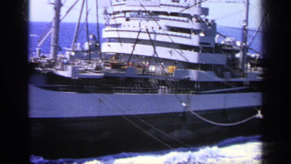 1963 Greece 8mm view of a large cargo ship passing in choppy blue water, with crew visible on deck near the superstructure.