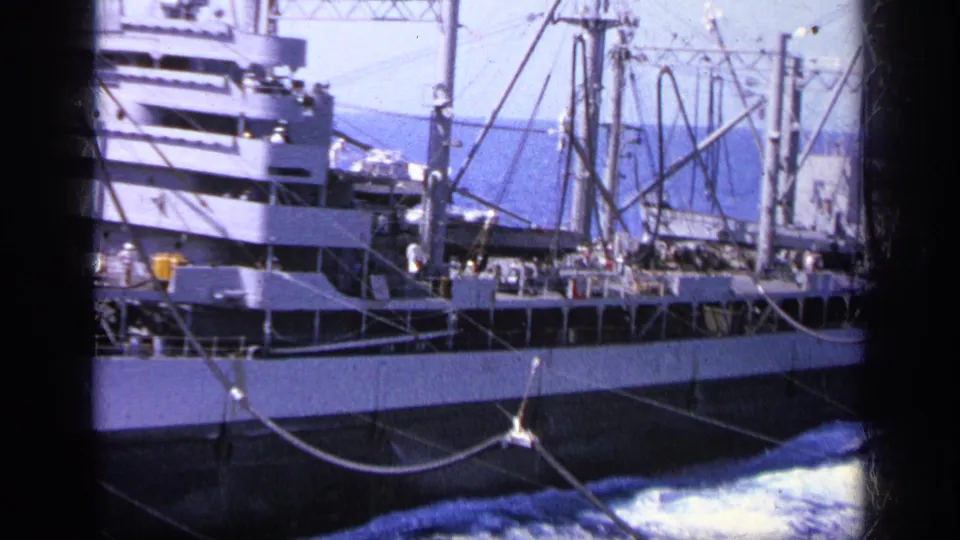 1963 Greece 8mm close side view of a cargo ship deck with masts, rigging, crew figures, and foamy ocean below.