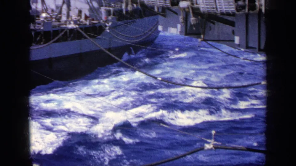 1963 Greece 8mm frame focused on the ship's wake and nearby hull, with crossing cables and part of the vessel visible at upper left.