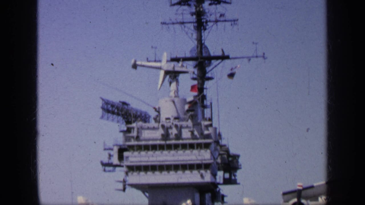 1963 Greece home-movie view of a U.S. Navy carrier island with radar mast and film gate borders visible.