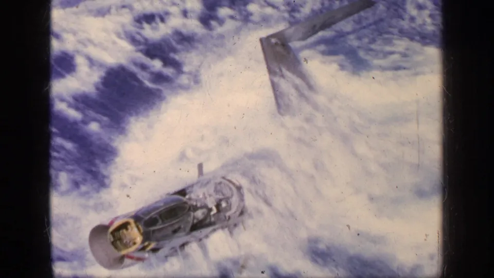 After impact, the aircraft is visible in turbulent water beside the carrier, surrounded by white foam and wake.