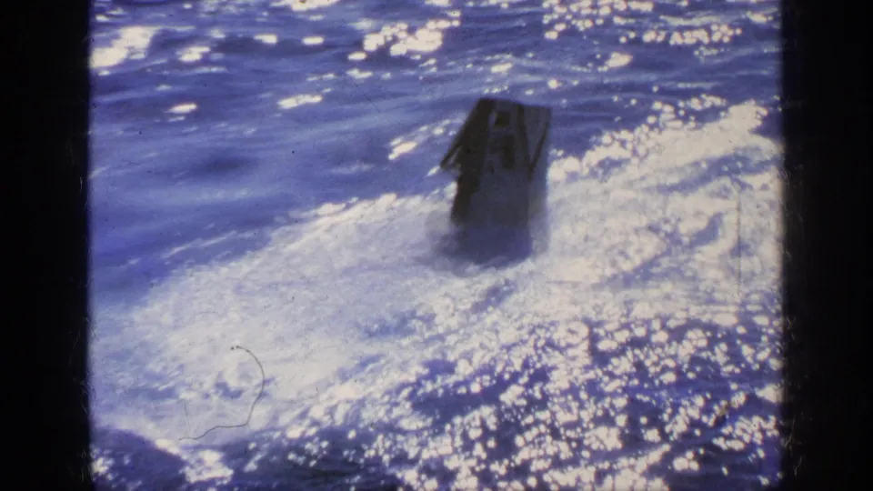 1963 Greece 8mm frame with a small boat rising in turbulent, glittering water under harsh reflected sunlight.