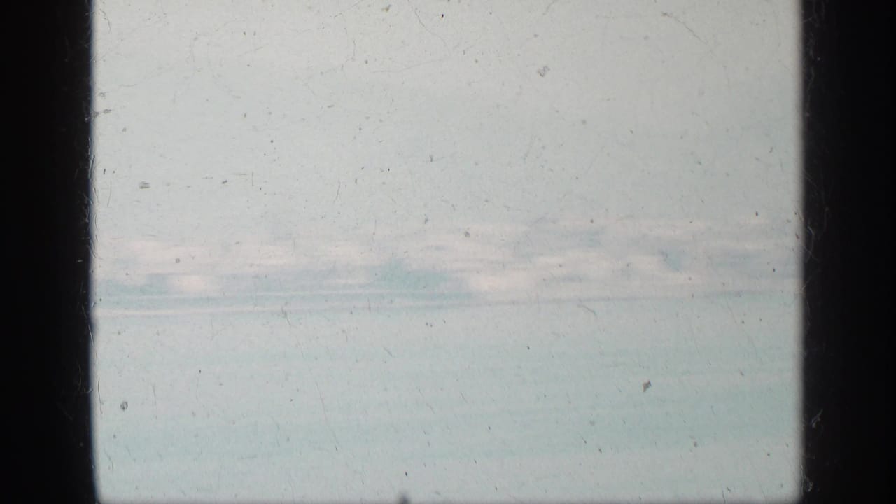 Hazy water and distant shoreline with mountains beyond the coast.