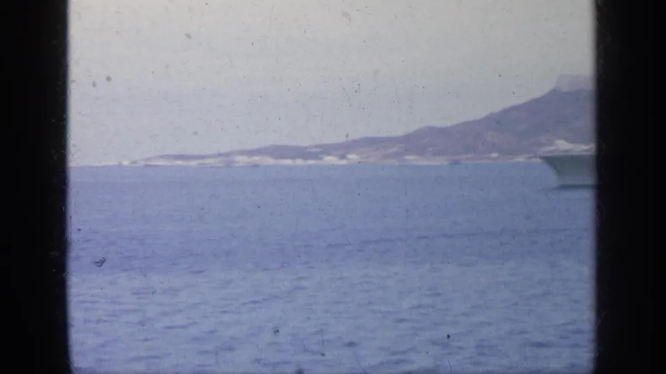 1963 Greece coastal view across blue water toward a distant shoreline and low hills.