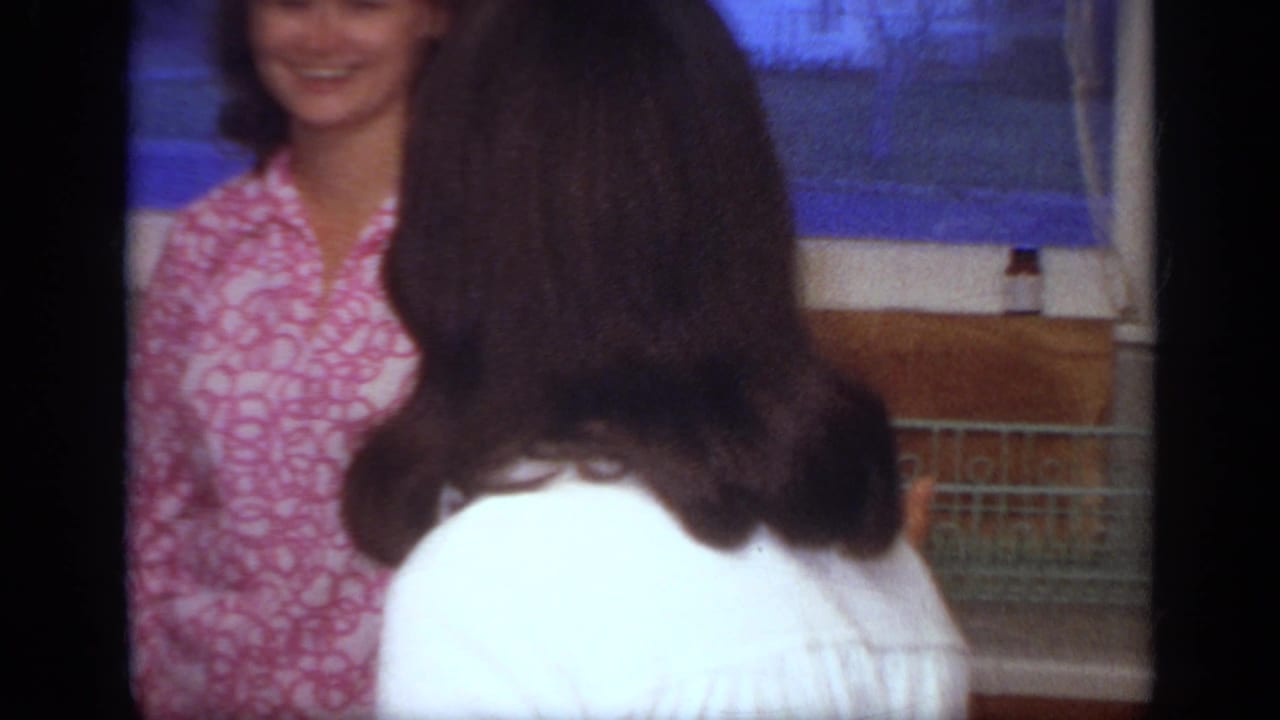 Home-movie view of two women in a 1968 California kitchen, one partly blocking the smiling woman near the window.