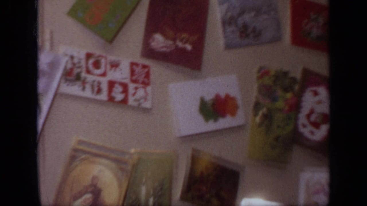 1968 California home-movie frame showing colorful greeting cards and decorations displayed on a refrigerator or nearby surface.