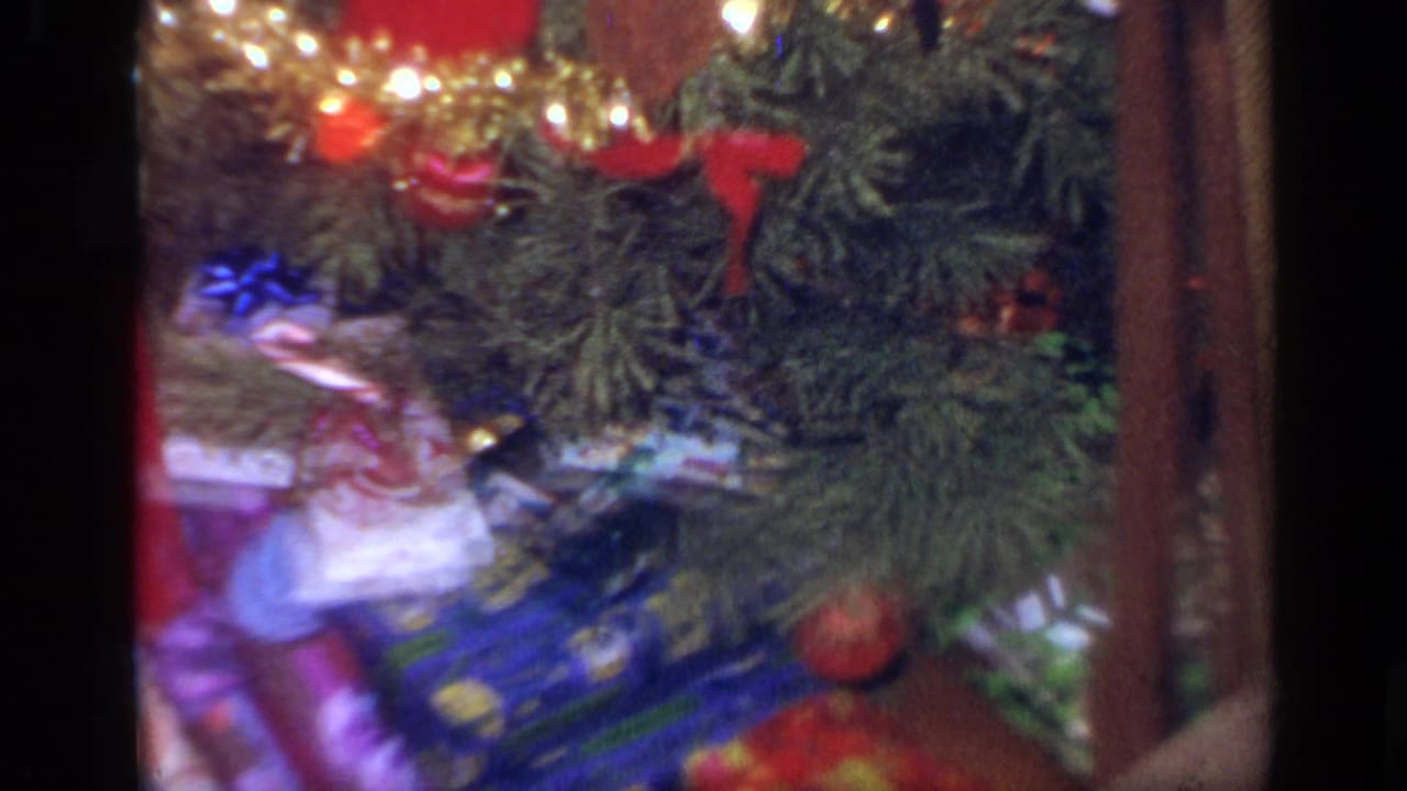 Close view of wrapped gifts beneath a decorated Christmas tree.