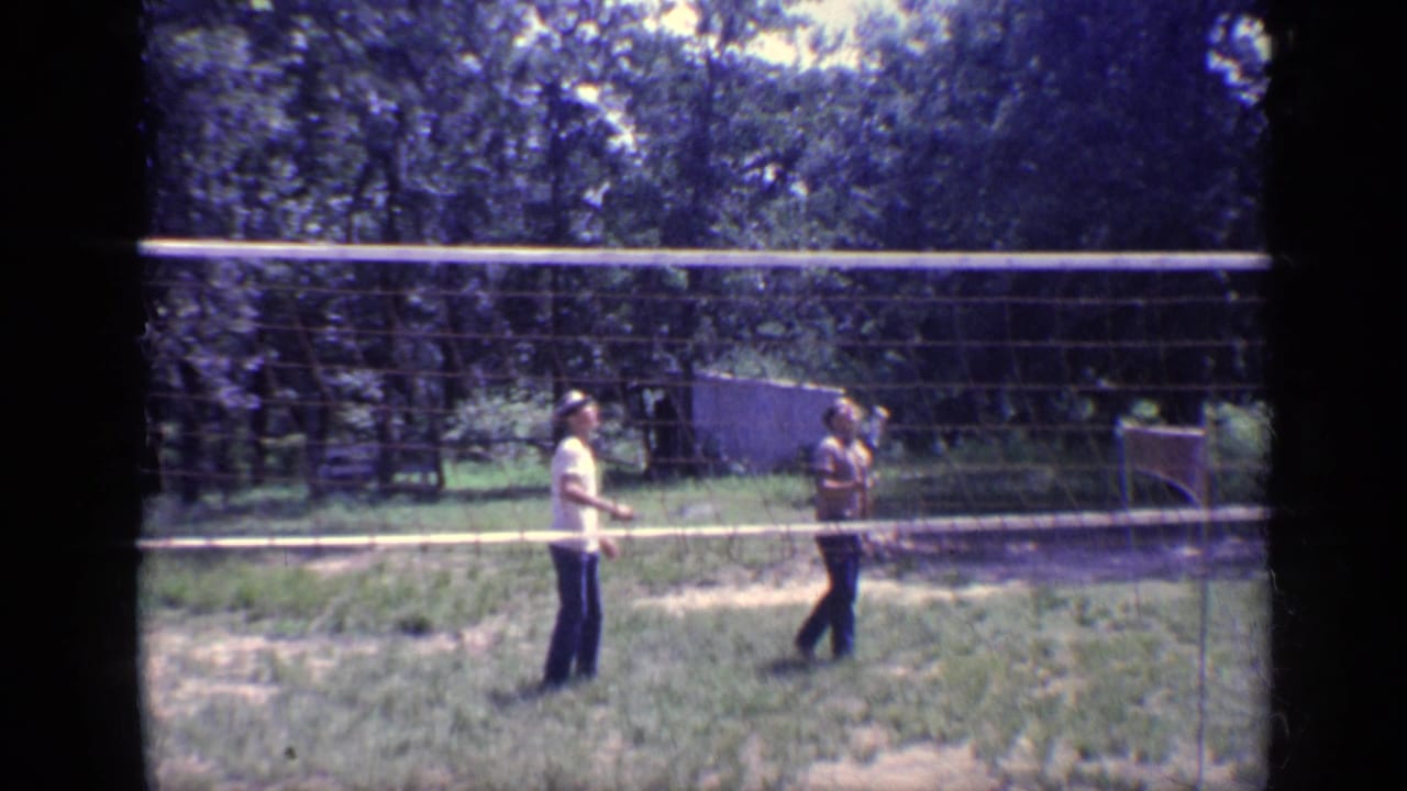 Two young men play badminton across a portable net in a wooded Florida yard, consistent with the 1968 home-movie metadata.