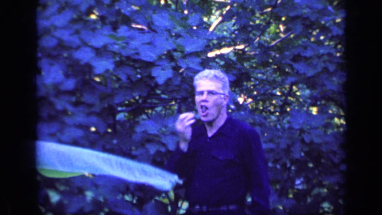 The man stands in the leafy Florida garden, appearing to taste or examine a small picked item near his mouth.