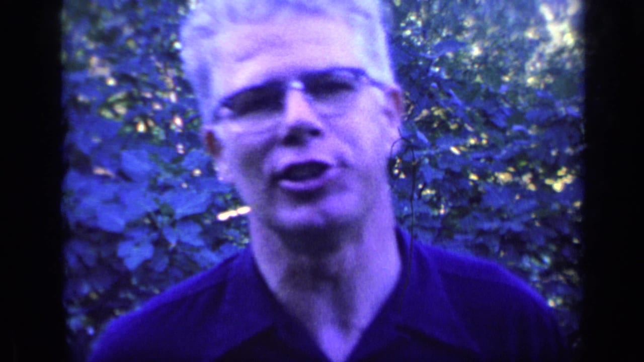 Close view of a white-haired man with glasses speaking outdoors.