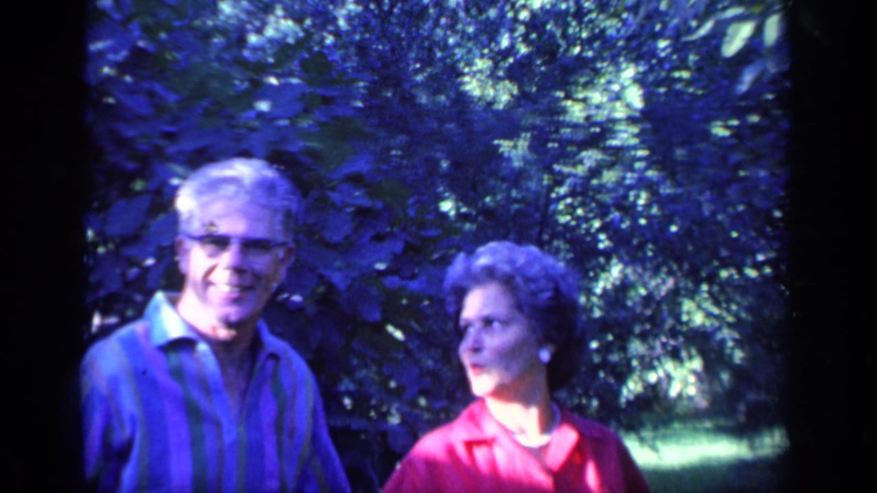 The couple stands together in a Florida garden, with the man facing camera and the woman turning toward him.
