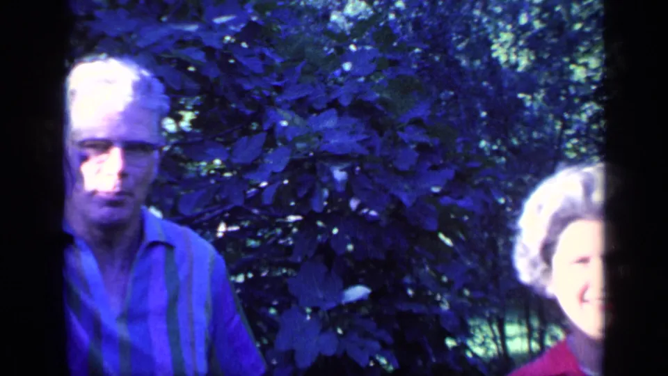 The man appears closer to the camera as the woman moves partly out of frame in the shaded Florida garden.
