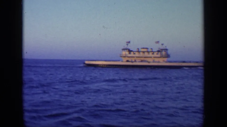 1968 Florida home-movie view of a large military-style vessel on calm ocean water with flags visible above the decks.