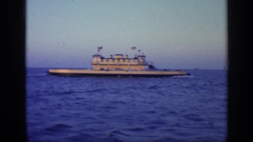 Side-on 8mm view of a large vessel in Florida waters in 1968, with flags and deck structures visible against the horizon.