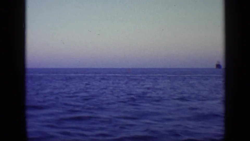 1968 Florida 8mm frame showing blue ocean, a faint wake or horizon line, and a small distant vessel near the right edge.