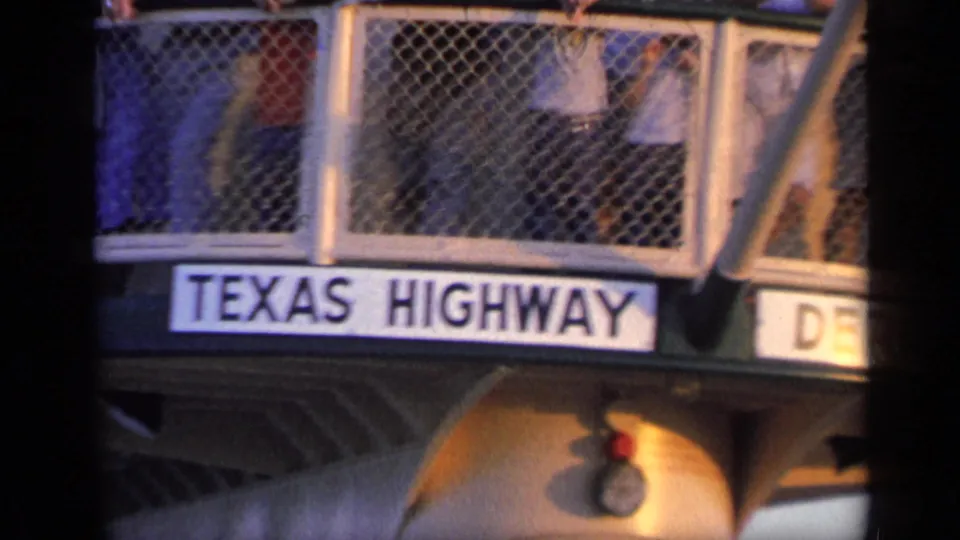 A readable Texas Highway sign is mounted on a vessel structure, with partial passengers visible behind a metal mesh railing.