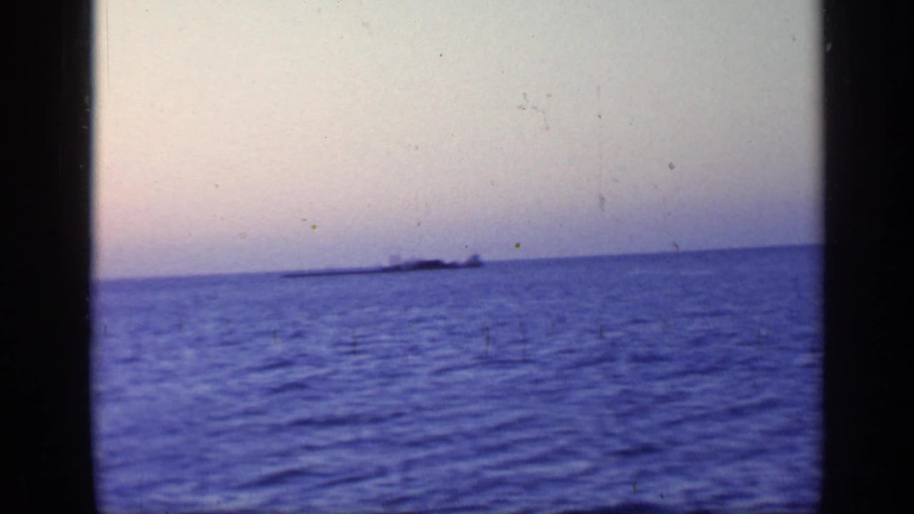 Open coastal water seen from a ferry in Florida, with a faint distant shoreline under a pale twilight sky.