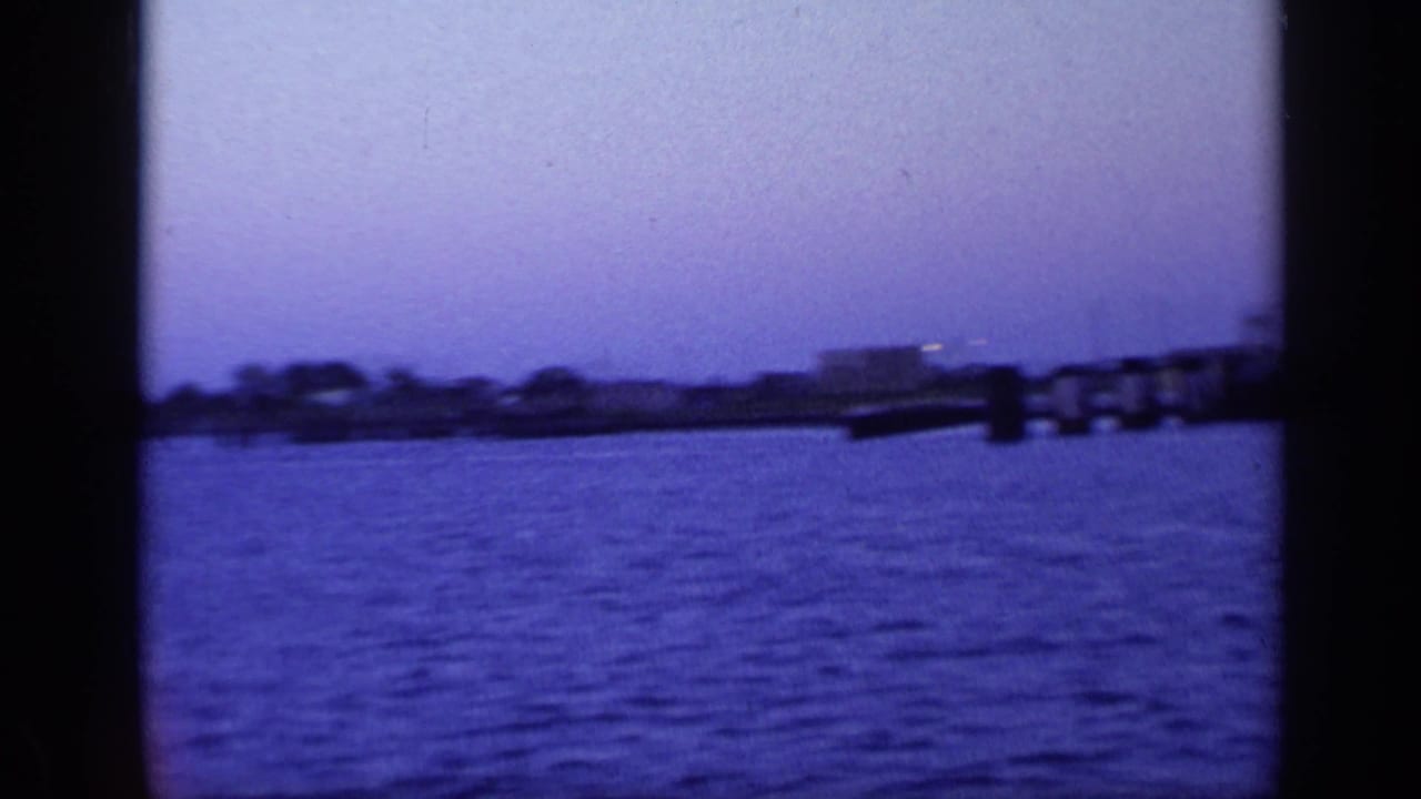 Harbor water with low shoreline, pier or dock structure, and dark film-frame borders.