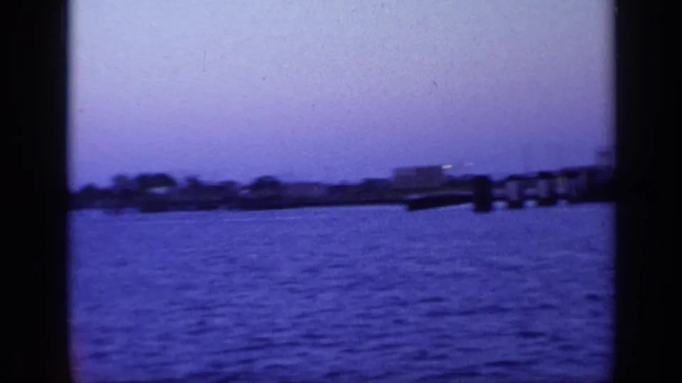 1968 Florida waterfront view with open water, distant buildings, and a pier or dock visible near the right edge.