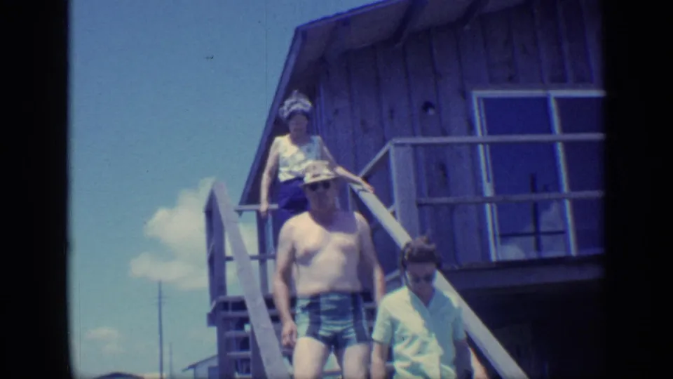 Near the end of the 1968 Florida clip, the man and woman continue down the wooden stairs as a second woman stands higher on the deck steps.
