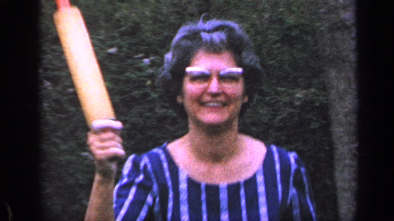 Woman in striped dress smiles outdoors while holding a rolling pin.