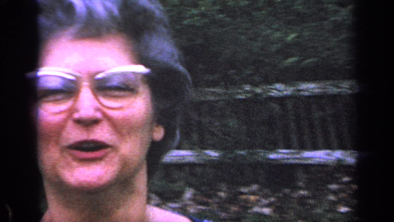 Close view of a smiling woman in white-framed glasses outdoors.
