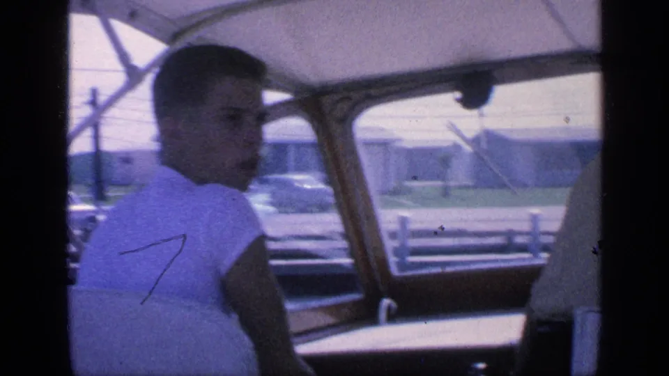 1968 Florida onboard yacht frame showing a passenger in a white shirt looking back near the helm and marina windows.