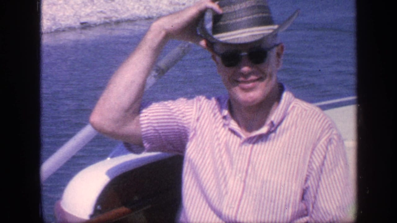 A man aboard a Florida boat adjusts his brimmed hat in bright sun, with blue water behind him.