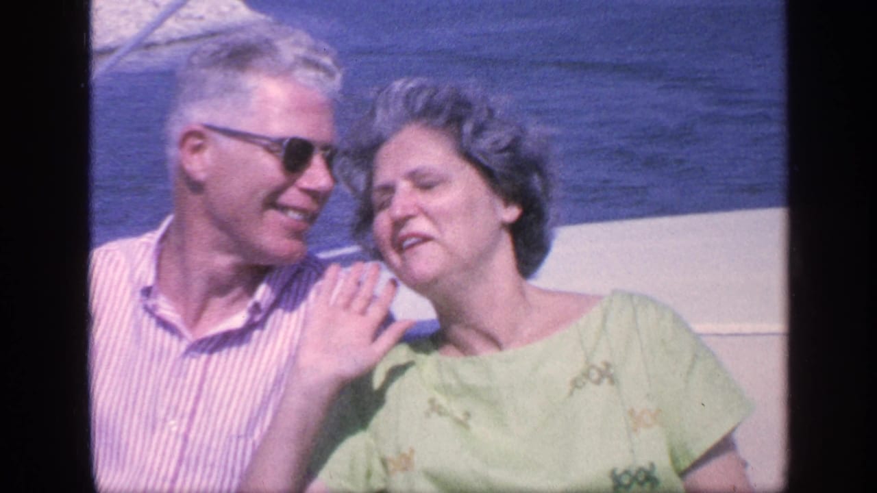 Older couple seated on a boat with blue water behind them.