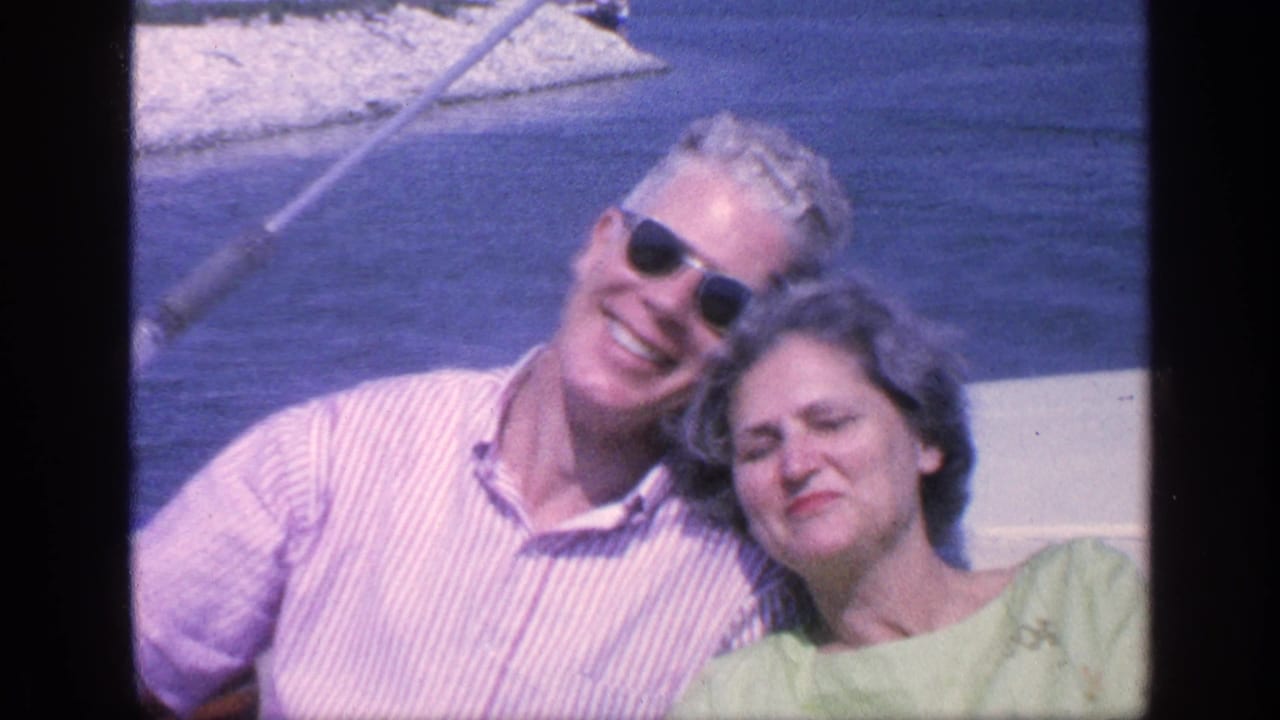 Smiling older couple posed together on a boat near the water.
