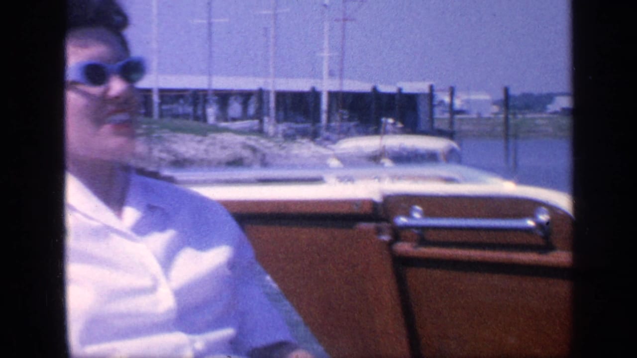 Woman in sunglasses seated in a boat beside water and docks.