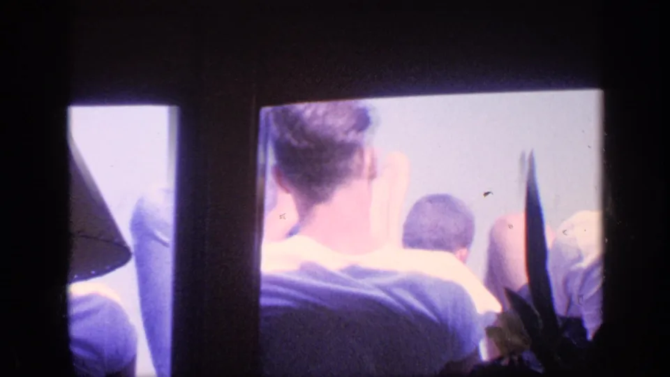 1968 Florida Super 8 frame showing passengers from behind inside a boat, with dark vertical framing and bright open light beyond them.