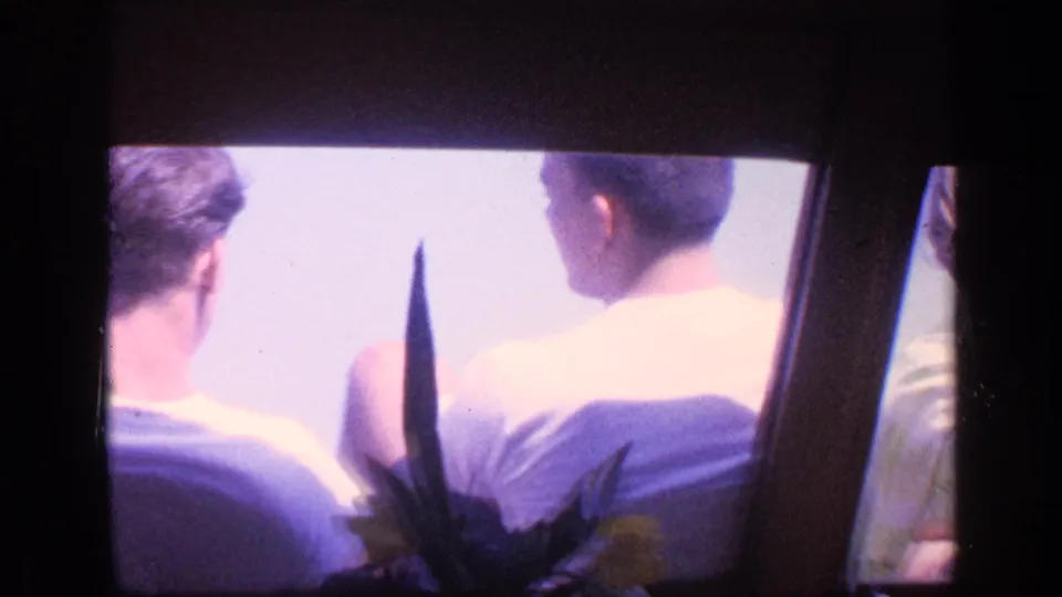 1968 Florida home-movie frame with several passengers viewed from behind inside likely boat or water taxi seating.