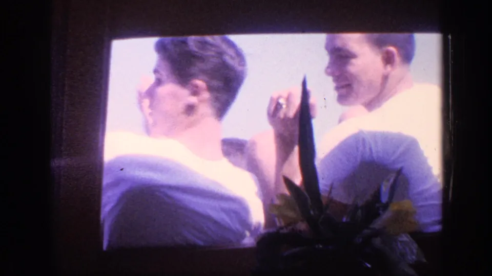 1968 Florida 8mm frame of two young men seated by a window, one seen in profile and the other smiling beside him.
