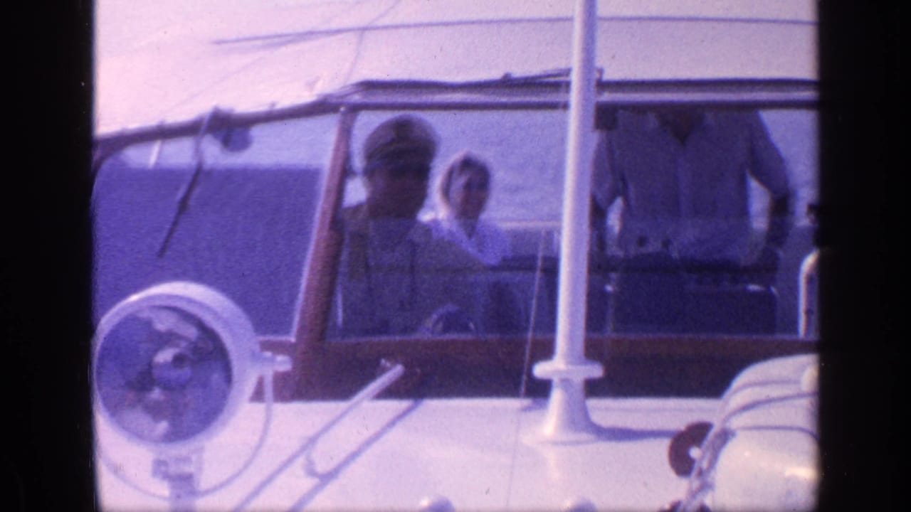 Passengers in a small motorboat seen through dark 8mm frame borders.