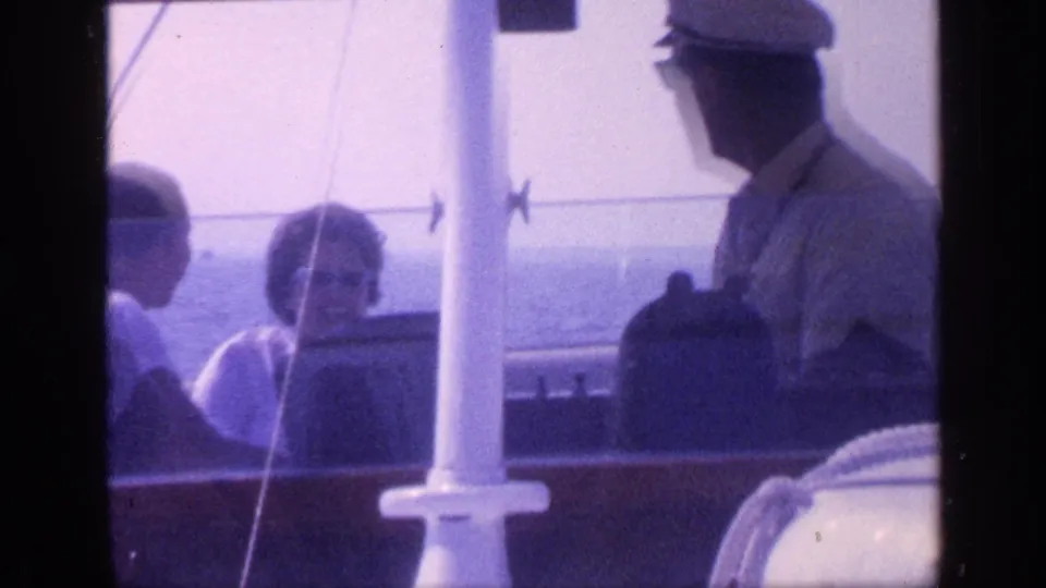 A capped adult stands near seated passengers aboard the boat, with white deck posts and calm Florida water behind them.