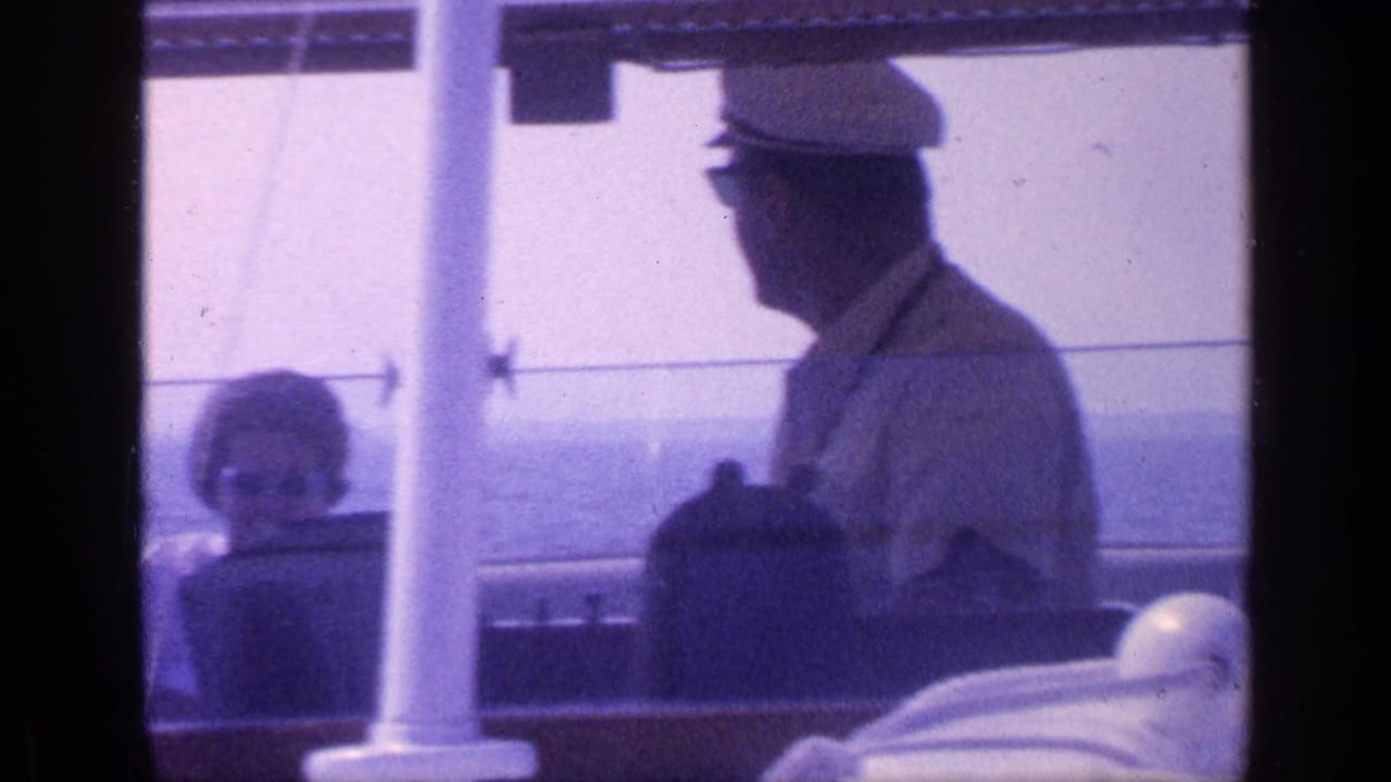 1968 Florida 8mm frame showing a man in a captain-style hat at the helm while a woman sits nearby on a boat deck.