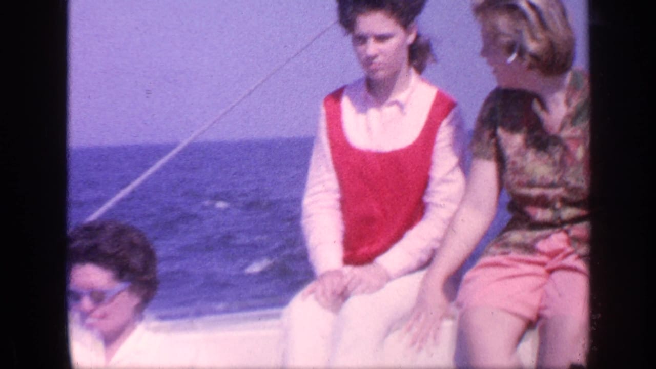 Adults seated on a boat with blue ocean behind them.