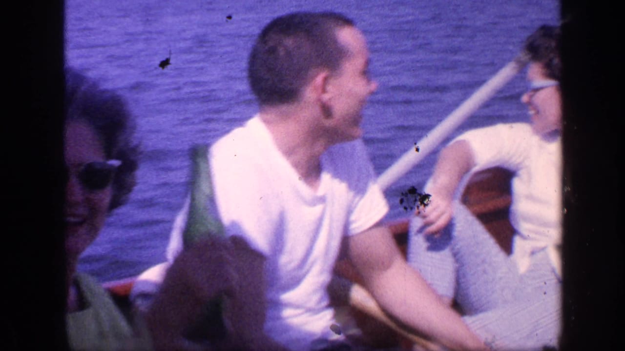 Adults seated in a small boat on blue water, with one man holding a green bottle.