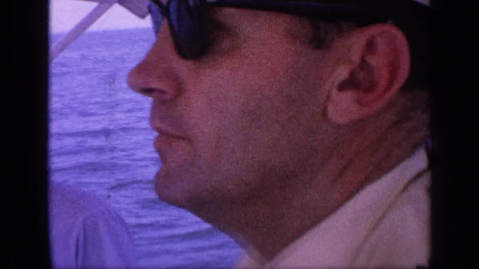1968 Florida home-movie frame with a close side profile of a man in dark sunglasses on the boat.