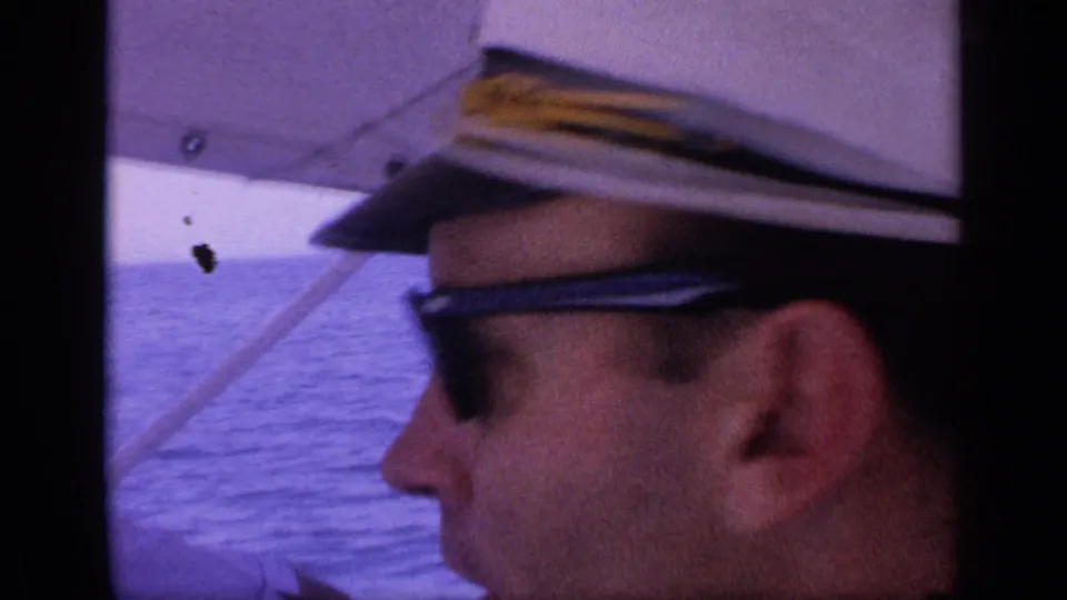 1968 Florida 8mm frame showing a man in a captain-style hat and sunglasses in close profile aboard a boat on open water.