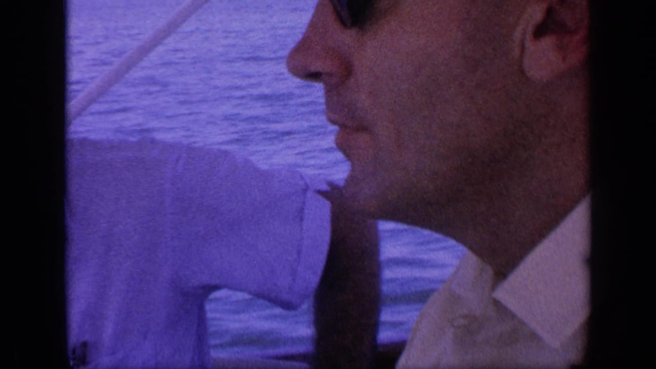 Close side view of a man in sunglasses on a boat with water behind him.