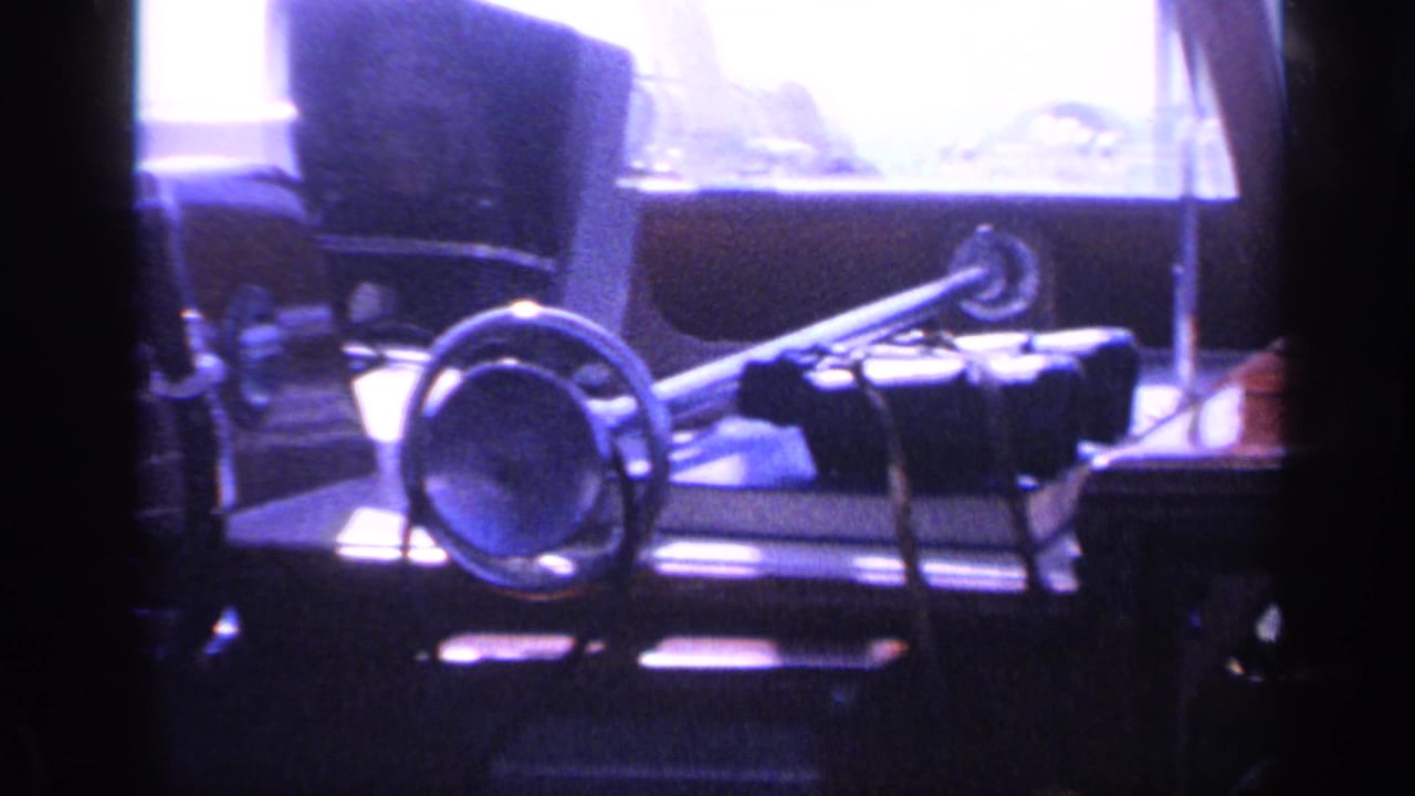 Close cockpit view from the 1968 Florida home movie, showing the steering wheel, horn, seat back, and overexposed window light.