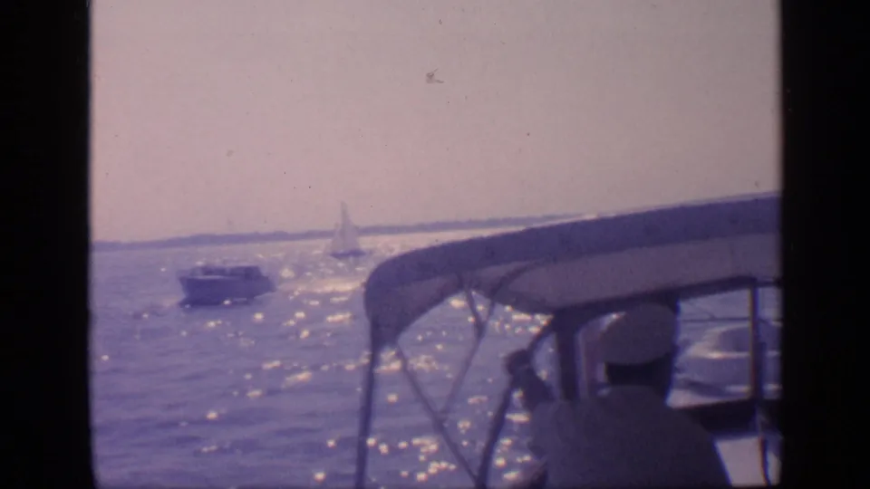 1968 Florida home-movie view from aboard a boat, showing the canopy, seated figures, sun glare, and distant vessels on the water.
