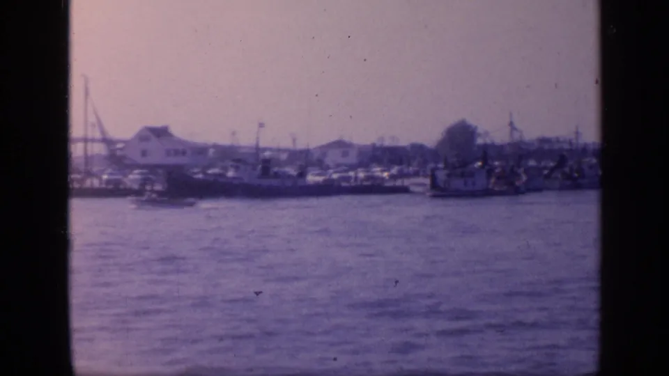 Final 1968 Florida harbor frame showing boats and low waterfront buildings across the water, with cranes and industrial shoreline details softened by aged 8mm color.