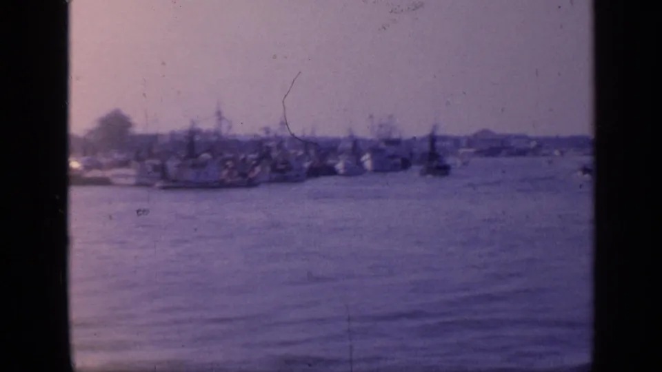 Soft 8mm Florida harbor frame with boats near the far shore and calm water filling the foreground.