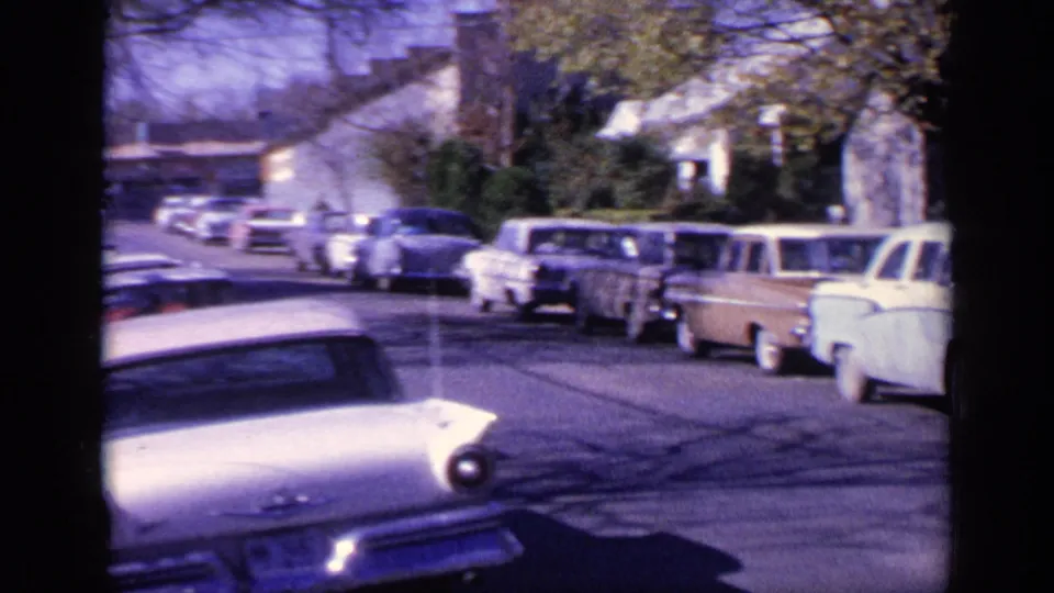 1968 Florida street scene with classic parked cars, residential buildings, trees, and bright home-movie exposure.