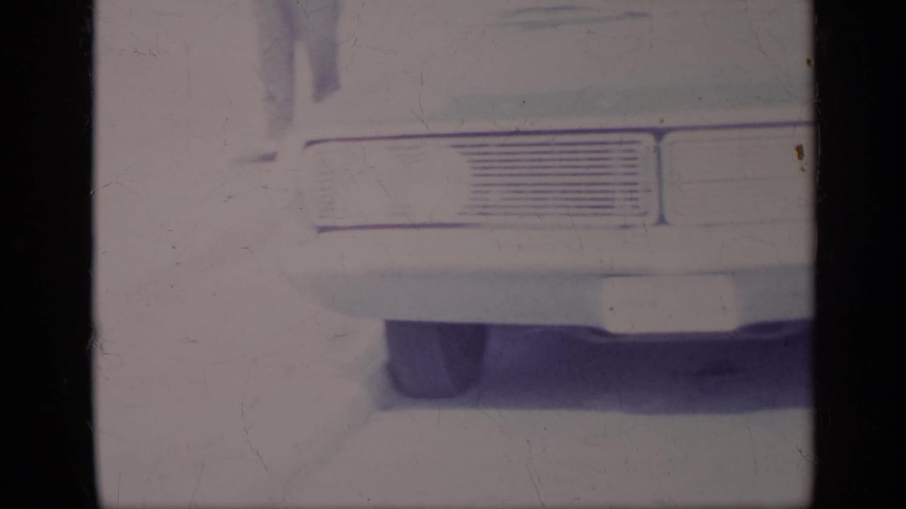 Close view of the rear of a parked car, partially cropped by the film frame.